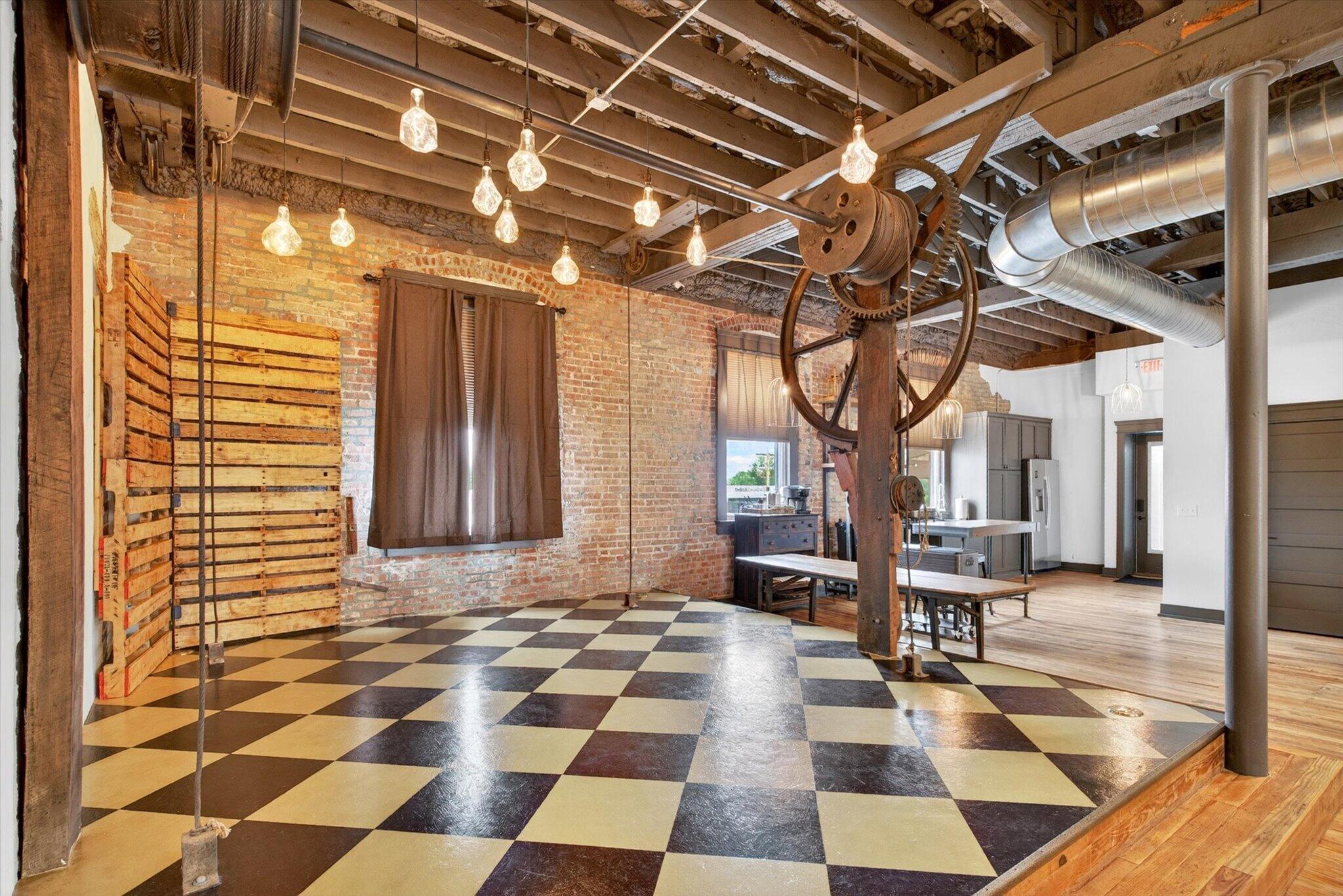 Historic interior with exposed brick, checkerboard floor, and original hoist