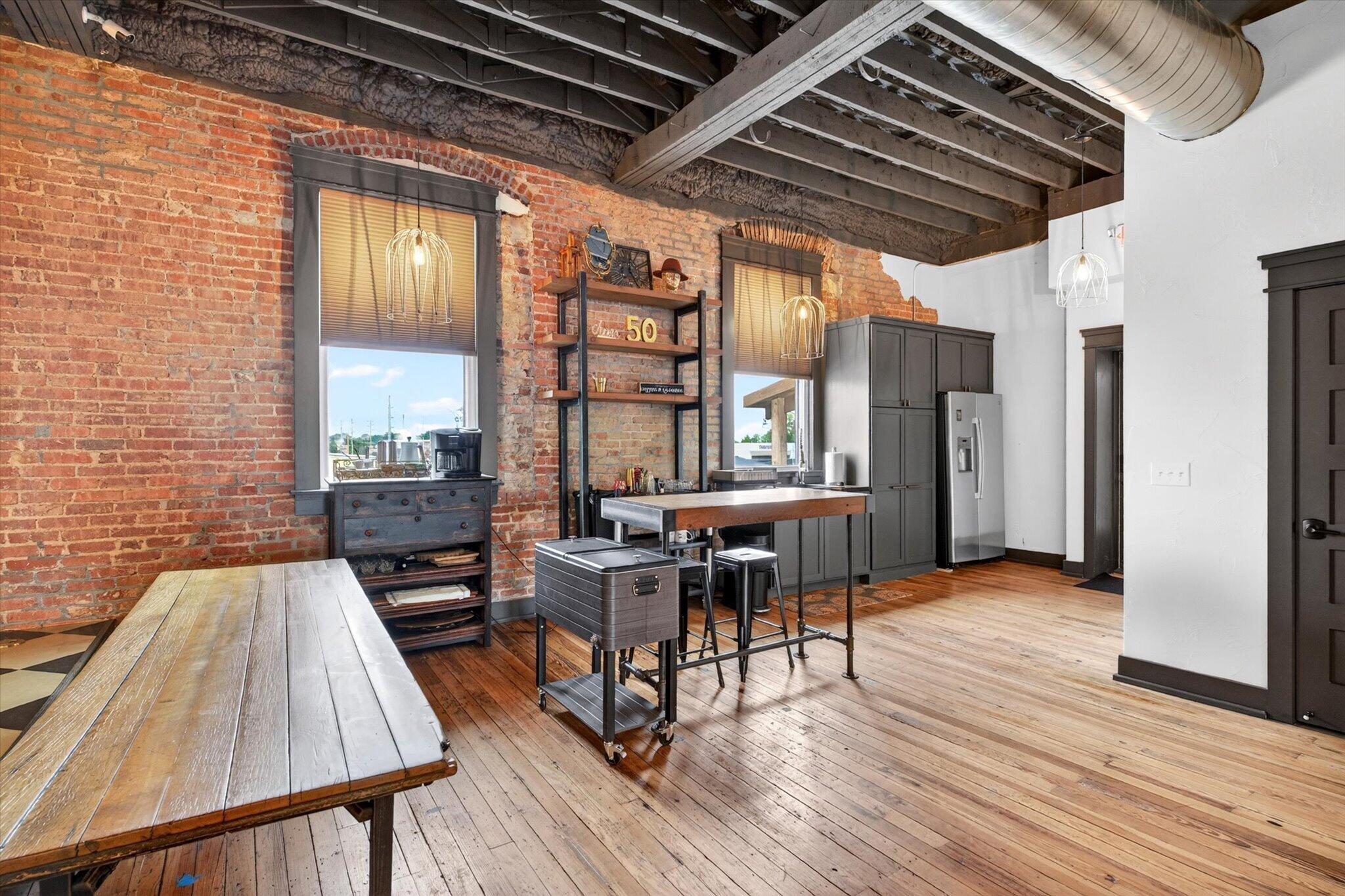 Shared kitchen with brick walls, tall windows, and a central counter