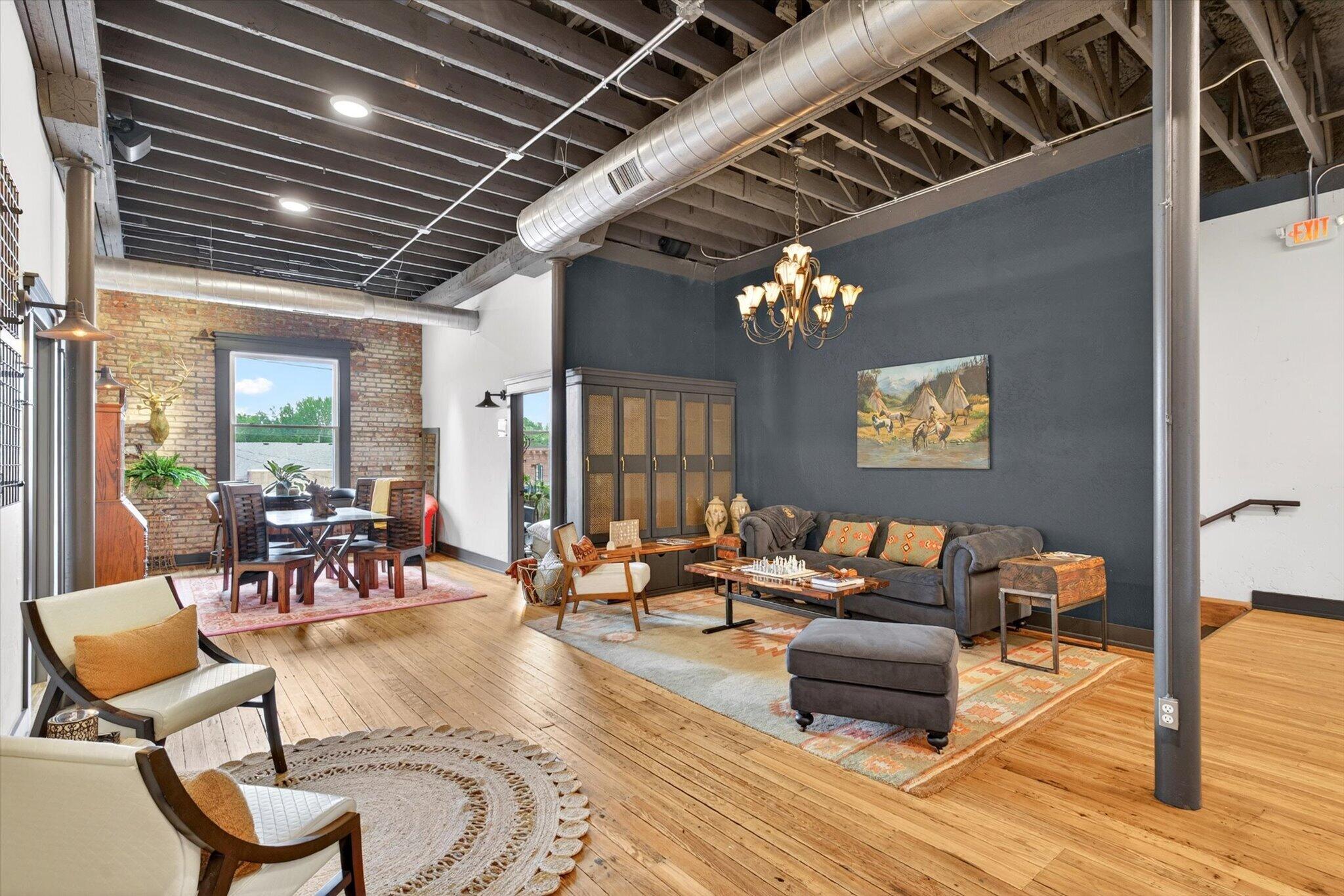 The light-filled lounge at Nixa Works with wood floors, exposed beams, brick walls, and seating
